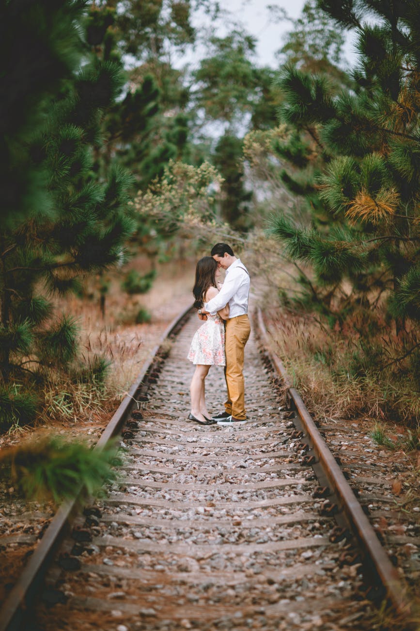 White couple hugging outside on train tracks in the woods