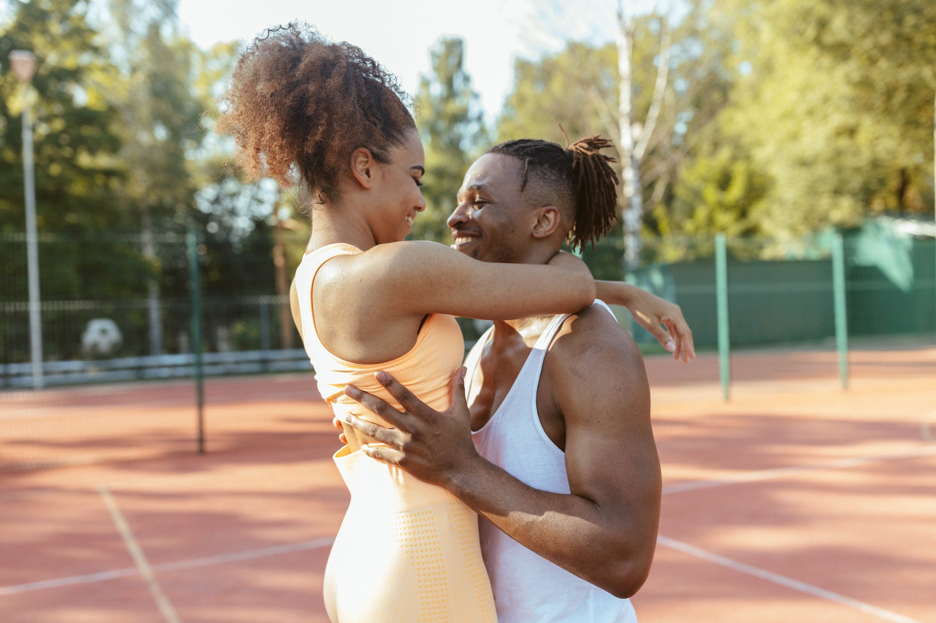Black couple embracing on a tennis court that met via elite Atlanta dating services