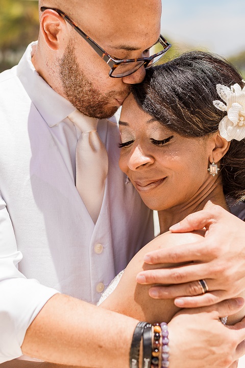 Black couple hugging at a beach wedding