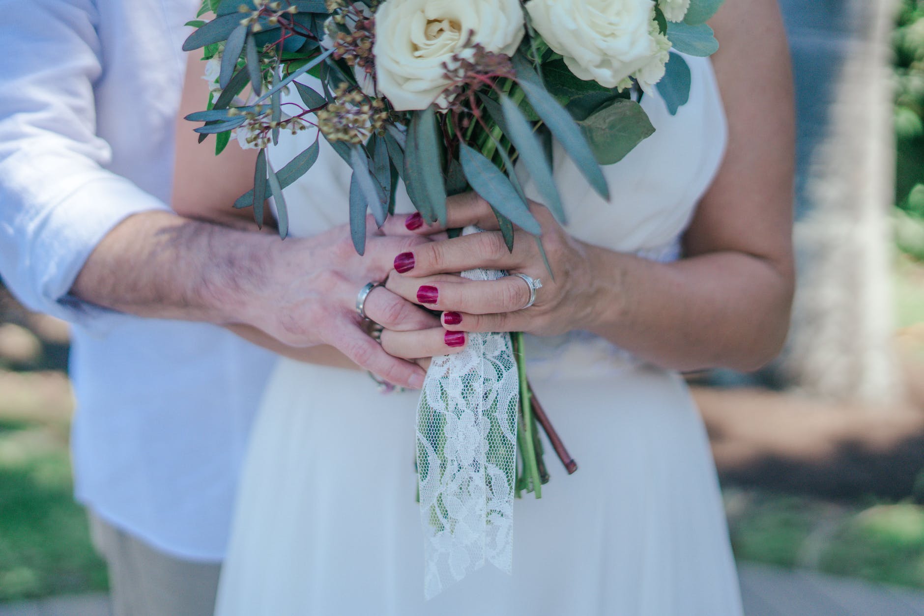 Newlywed Caucasian couple holding a bouquet of white flowers