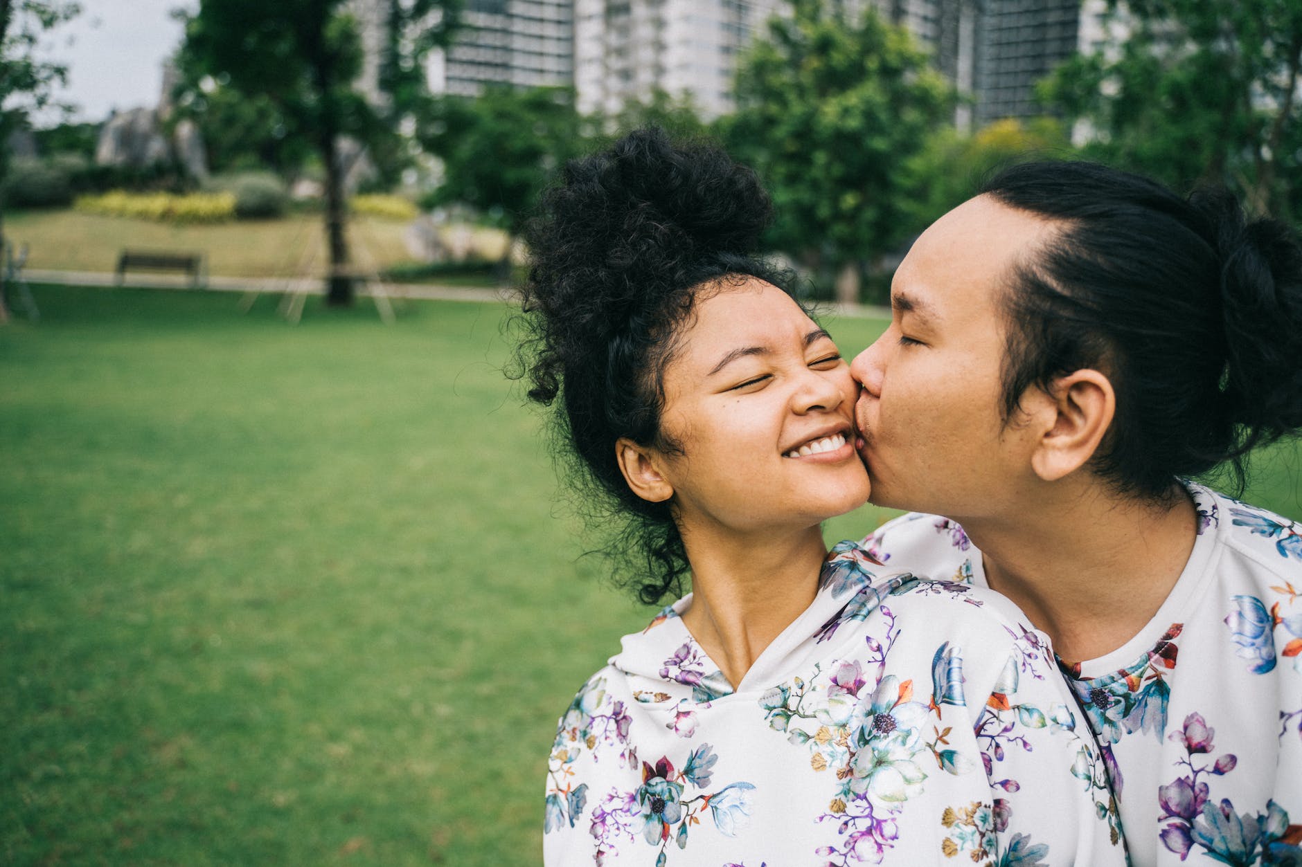 Asian couple kissing and cuddling in a park