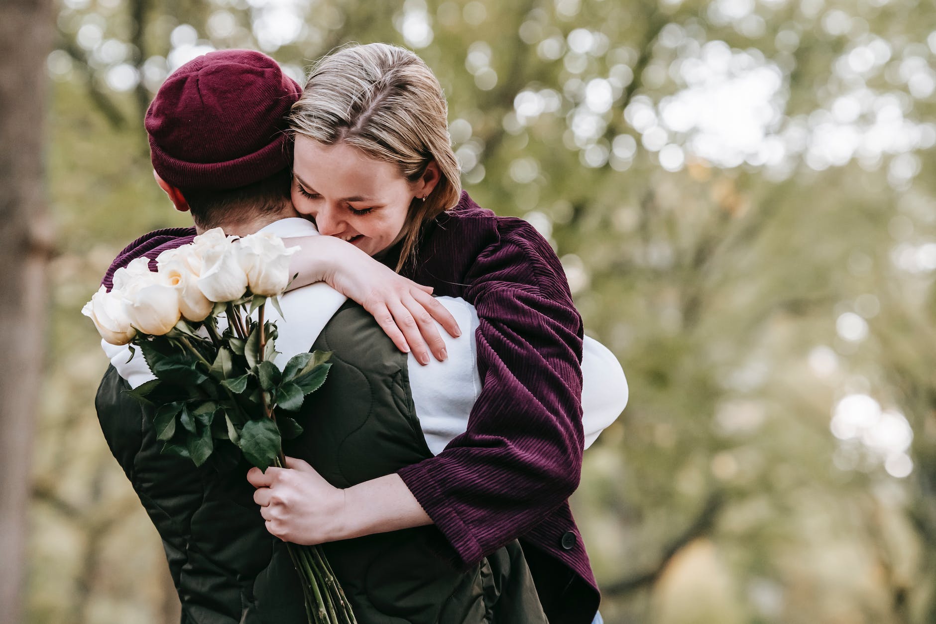 Caucasian couple hugging while woman holds white flowers