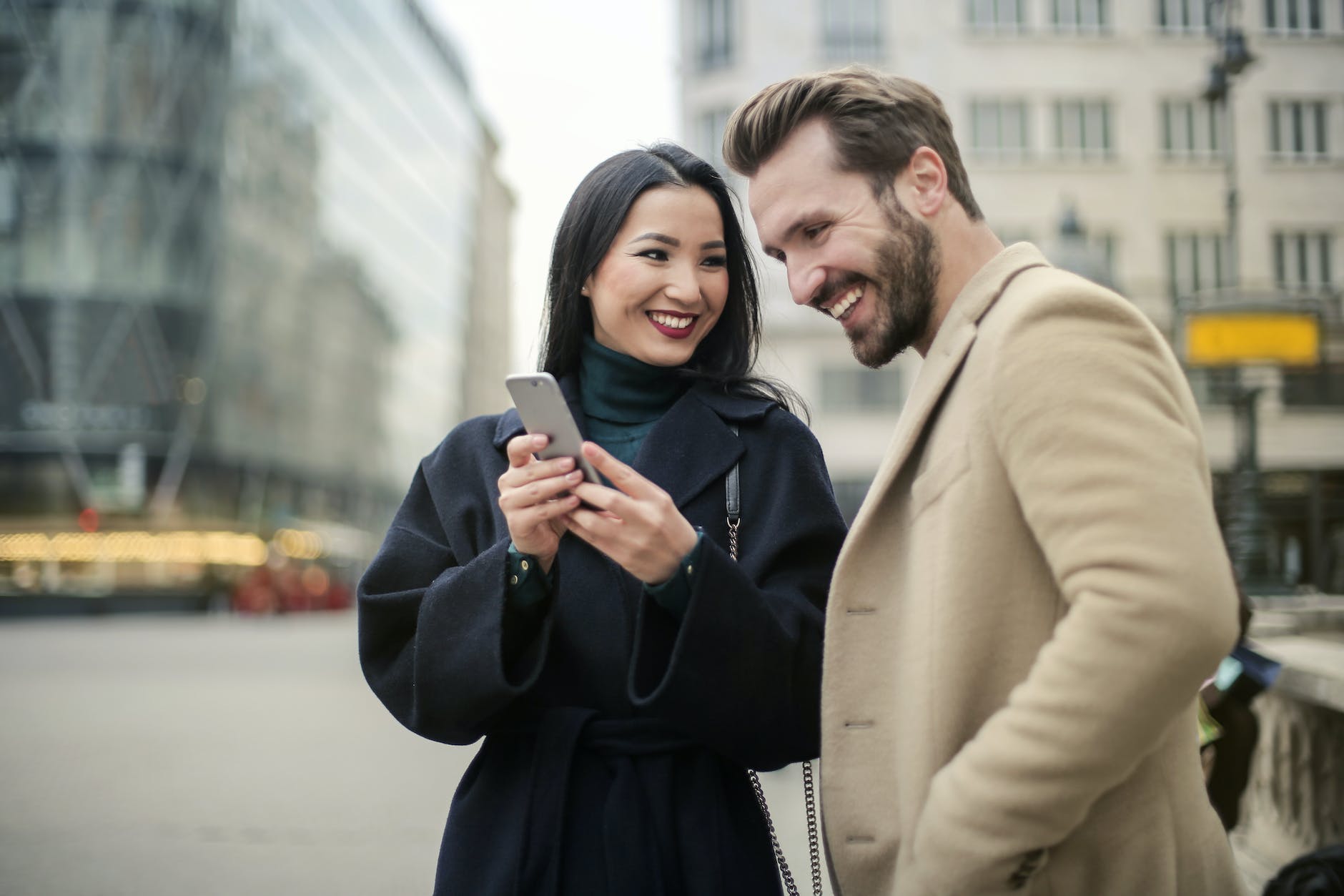 Interracial couple paired by matchmakers in Baltimore standing on a city street smiling at a cell phone