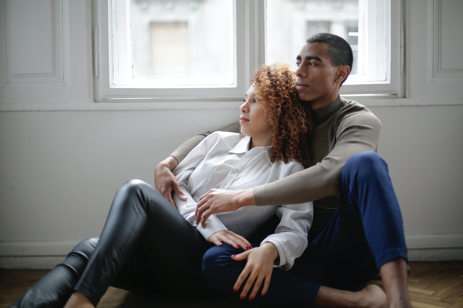 African American couple cuddling by a window