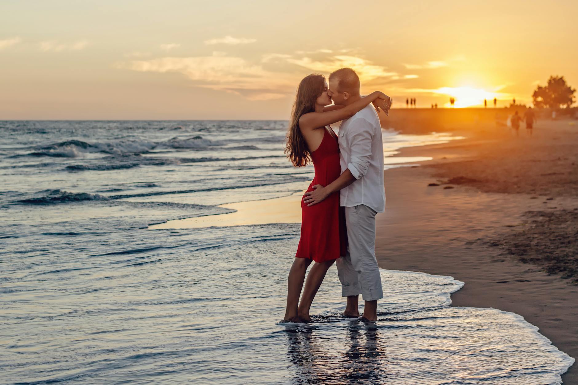 Caucasian couple united by Cincinnati matchmakers kissing on a beach at sunset with their feet in the water