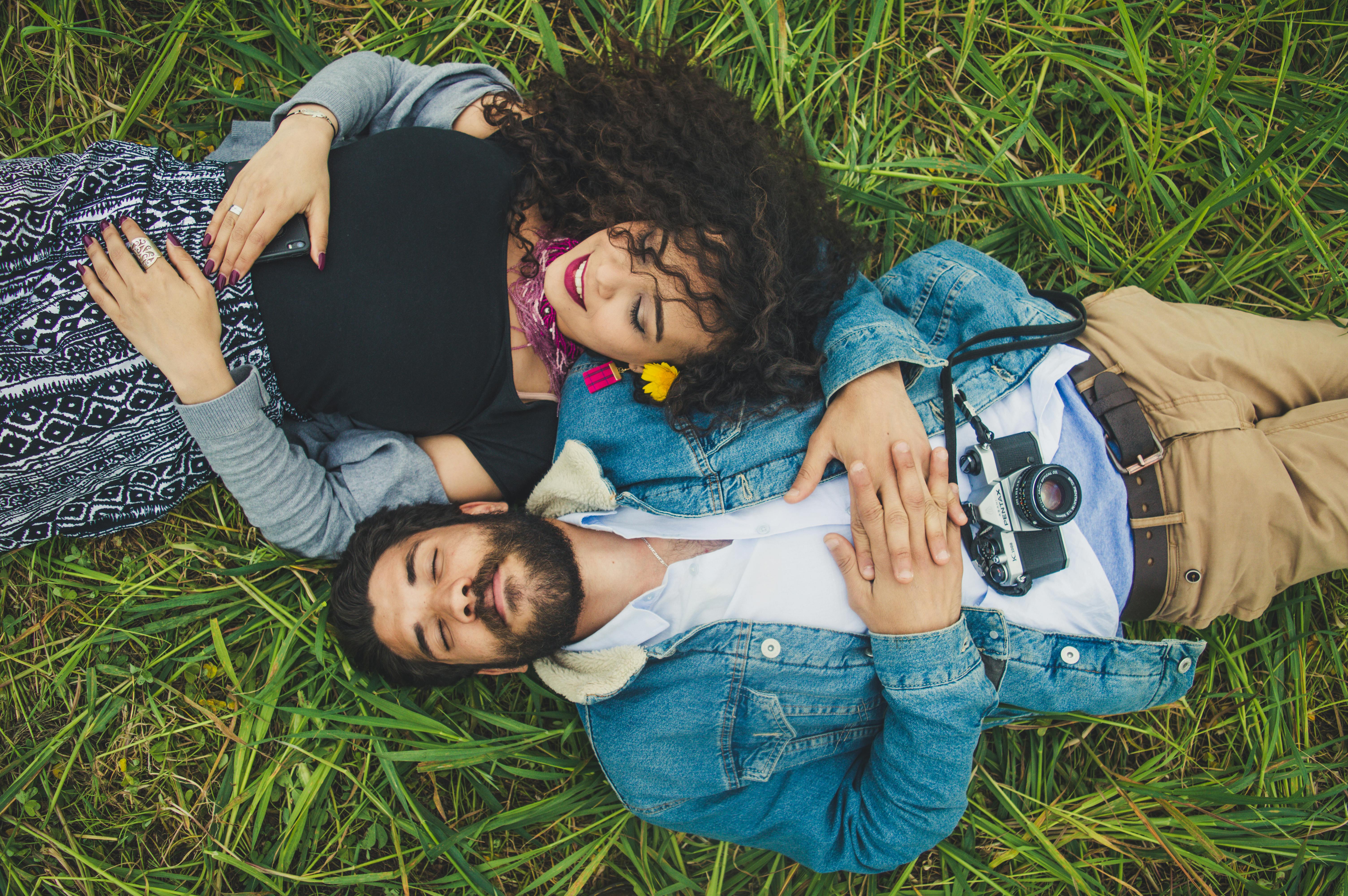 Cute couple paired by matchmakers in Austin laying down grassy in a field