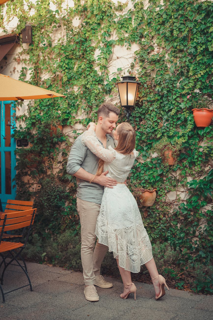 White couple introduced by matchmakers in Maryland embracing near a street light and ivy wall