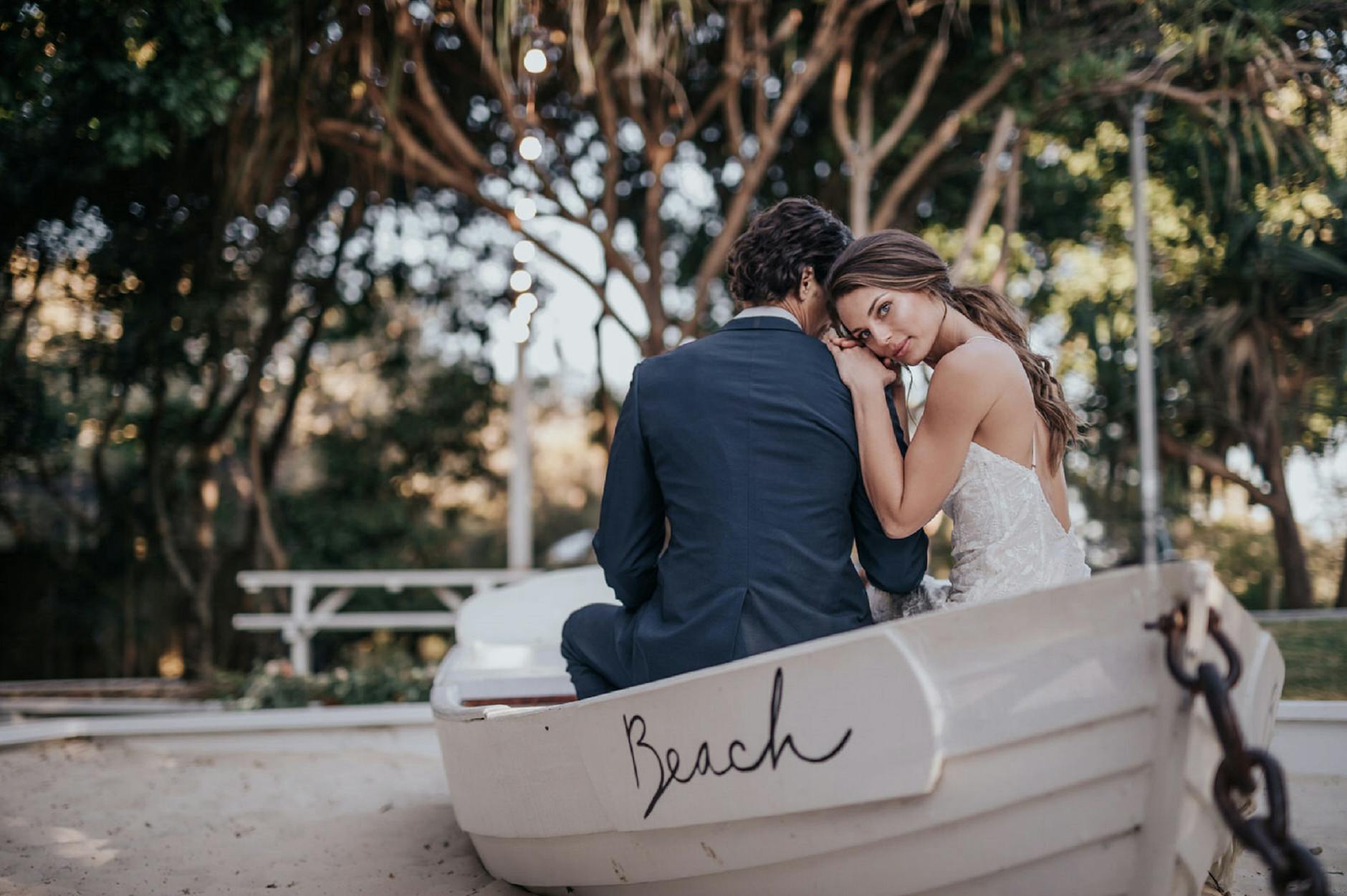 Newlywed couple united by Fort Lauderdale matchmakers sitting in a white boat on the beach on their wedding day