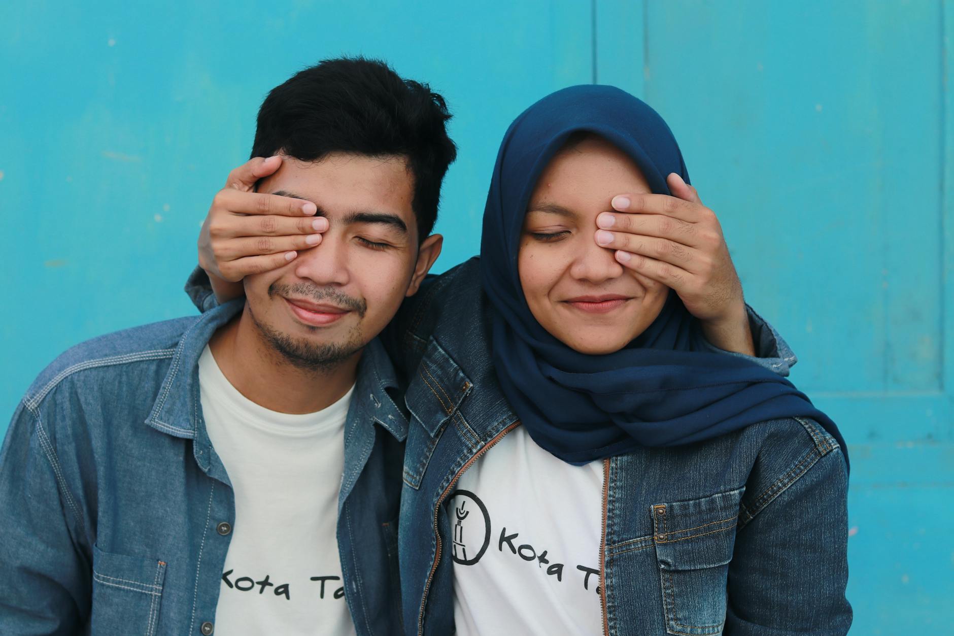 Asian couple paired by matchmakers in St. Louis sitting down hugging with their hands over their eyes