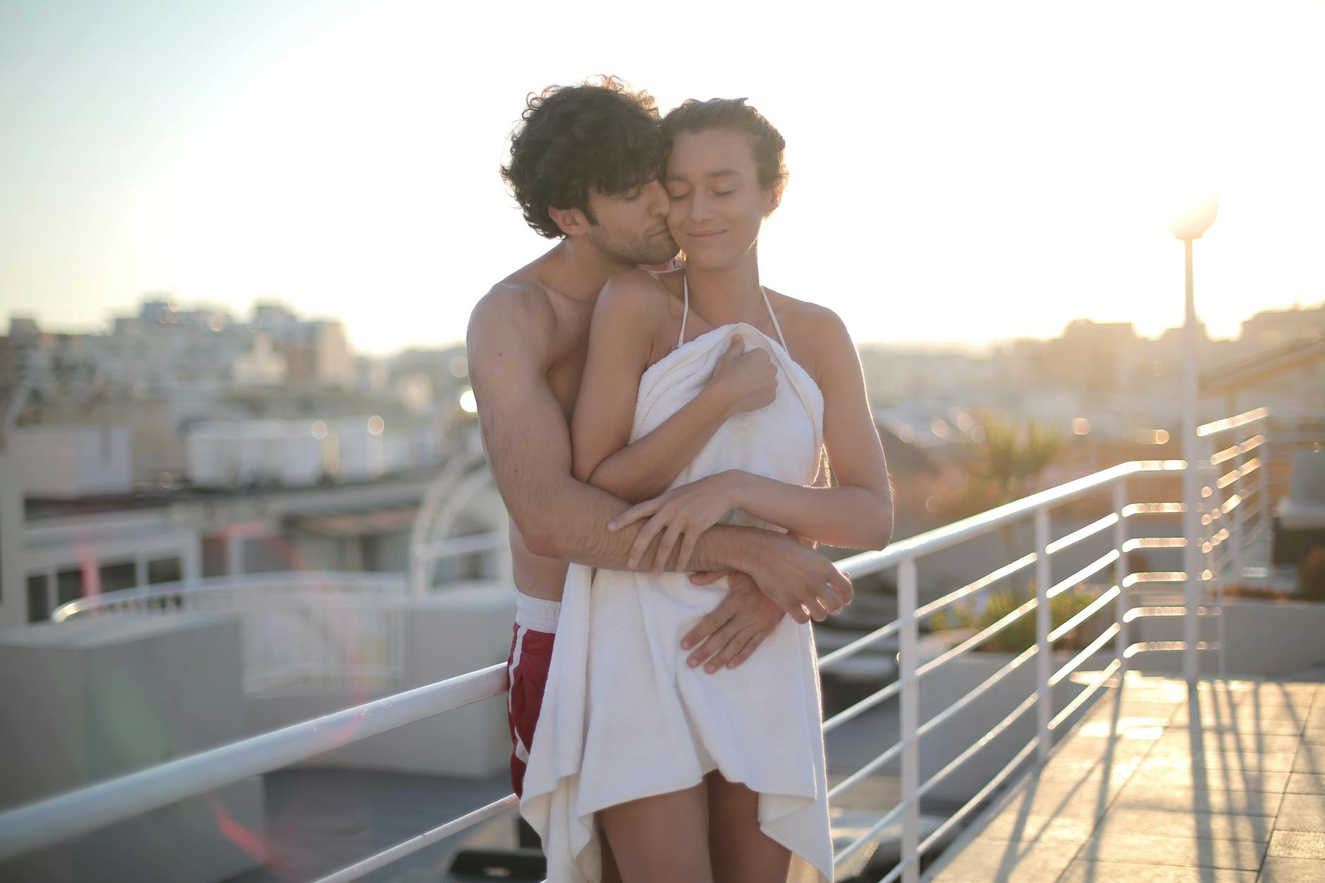 White couple standing outside hugging while holding a towel