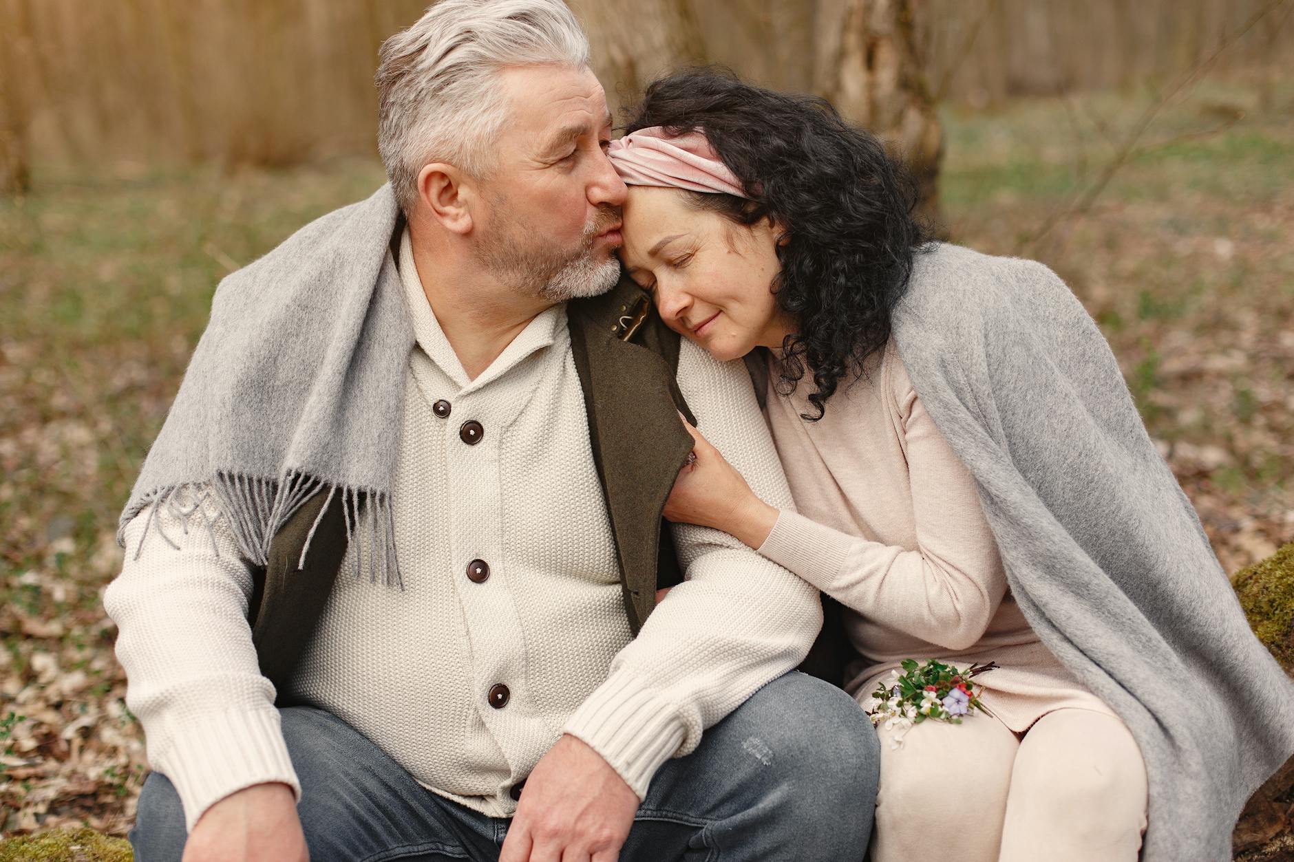 White couple sitting on a tree log that are an example of dating in your 60s
