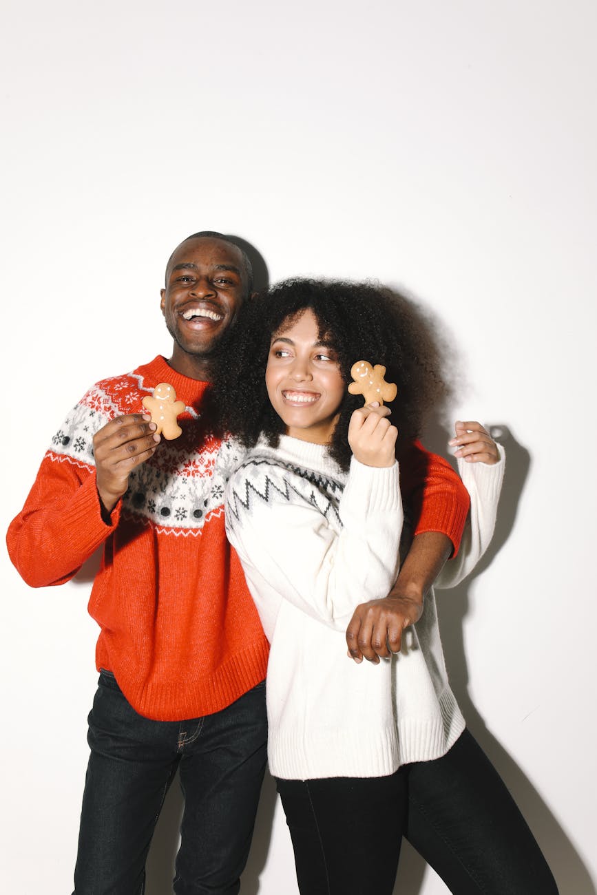 African American couple paired by matchmakers in Raleigh wearing Christmas sweaters while holding gingerbread cookies