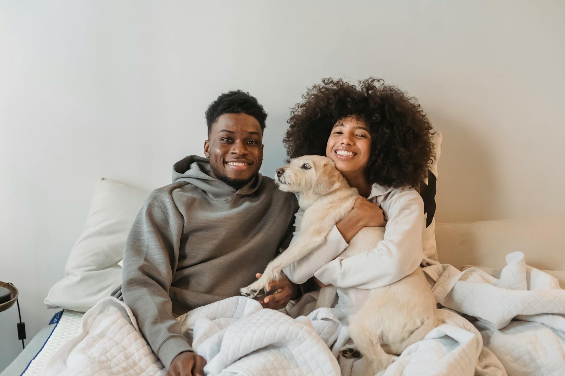 African American couple united my matchmakers in Seattle holding a dog while sitting on a bed