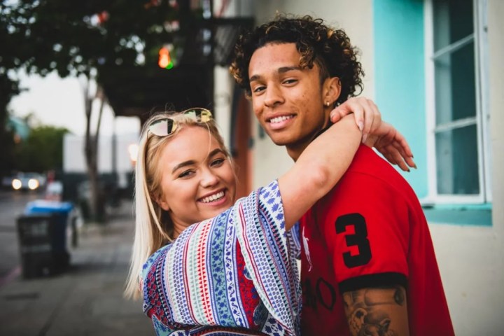 Interracial young couple hugging on the sidewalk and smiling