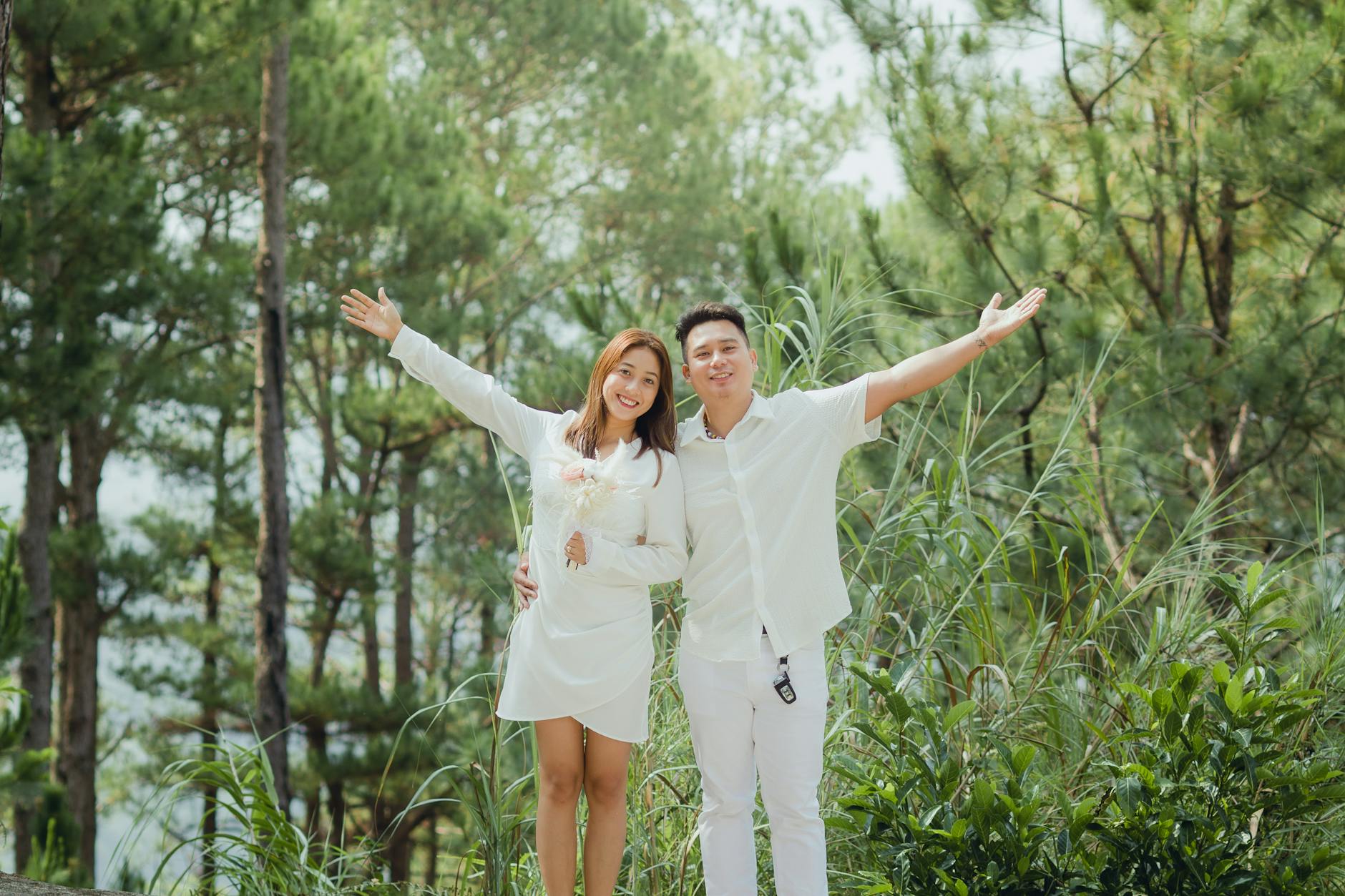Happy Asian couple wearing white standing and smiling while stretching out arms with love