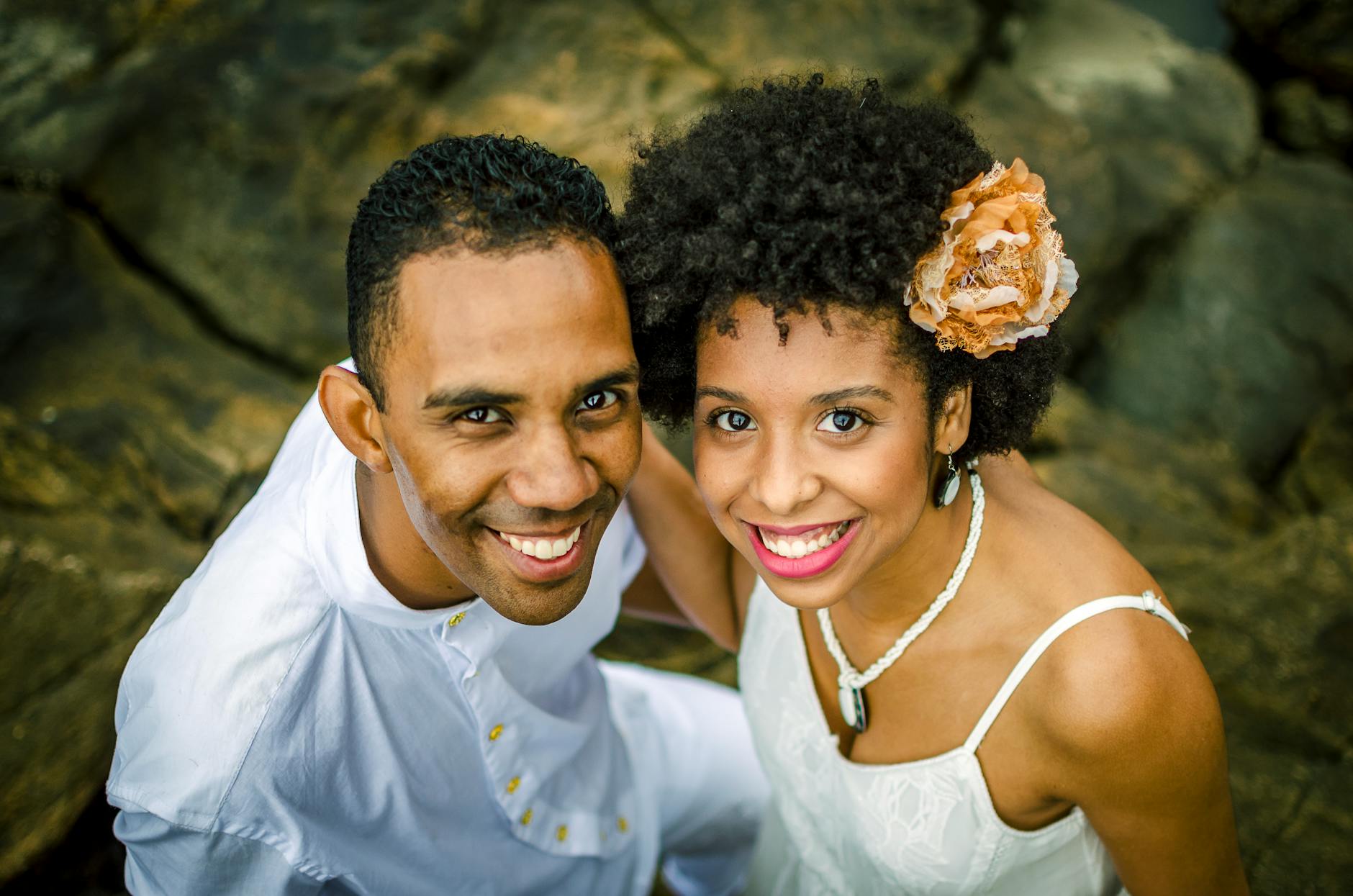 Black couple embracing and smiling at the camera while standing near rocks