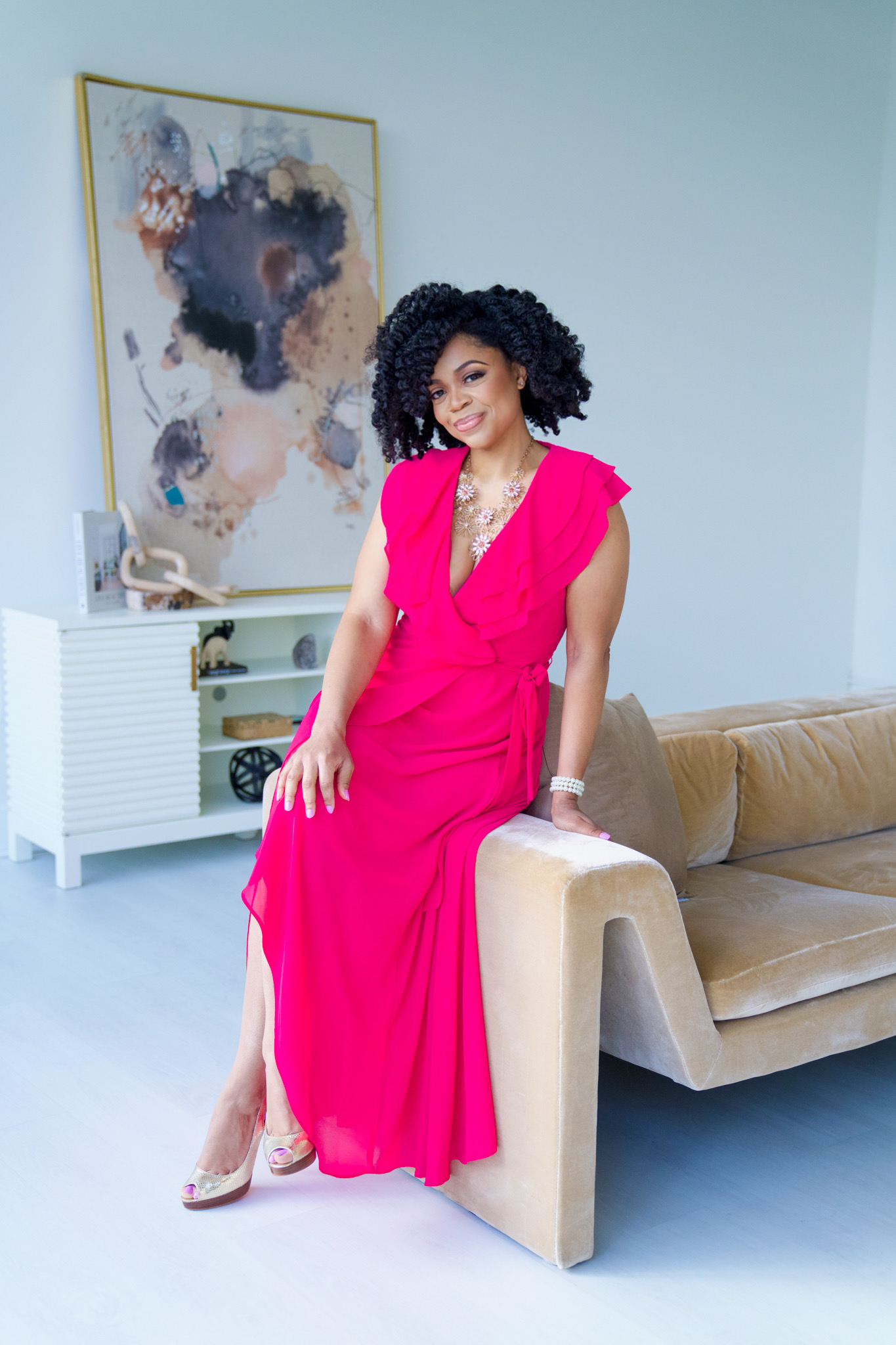 Professional black matchmaker Lauren Sanders wearing a pink dress and sitting on couch armrest