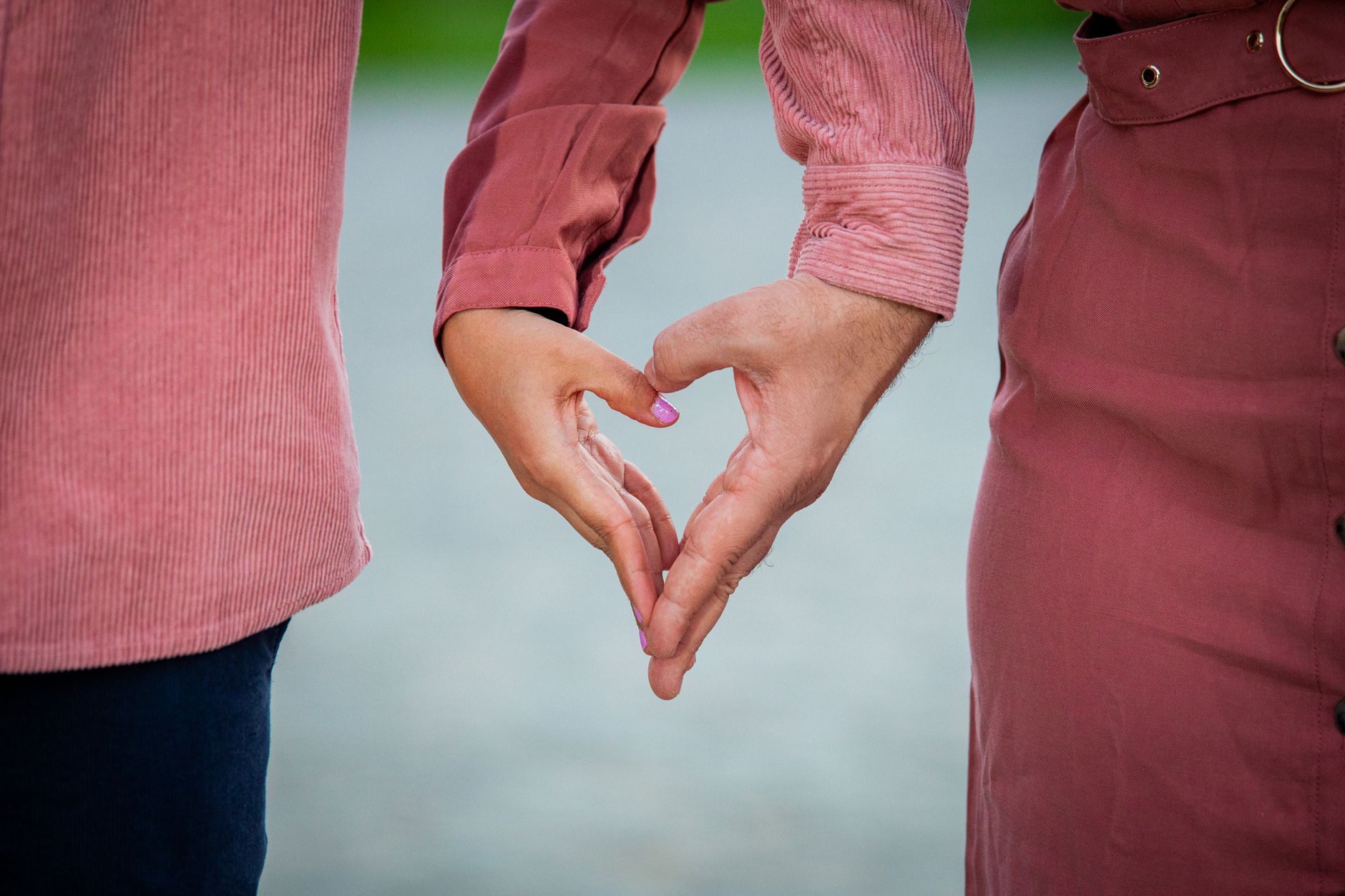 Caucasian couple matched by dating coaches forming heart hands while standing