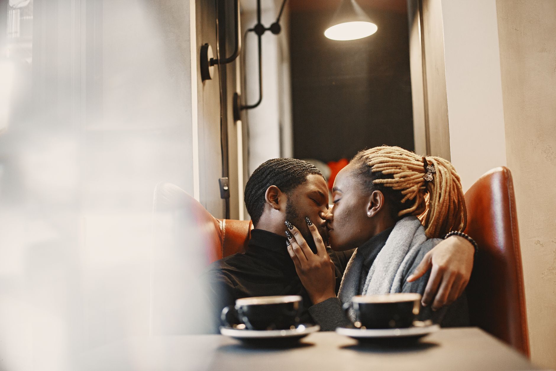 African couple kissing in a cafe near two cups of coffee