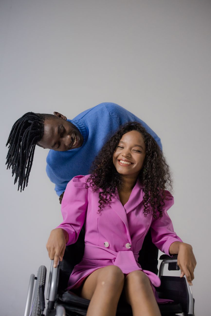 Disabled dating black couple smiling at each other while woman sits in a wheelchair